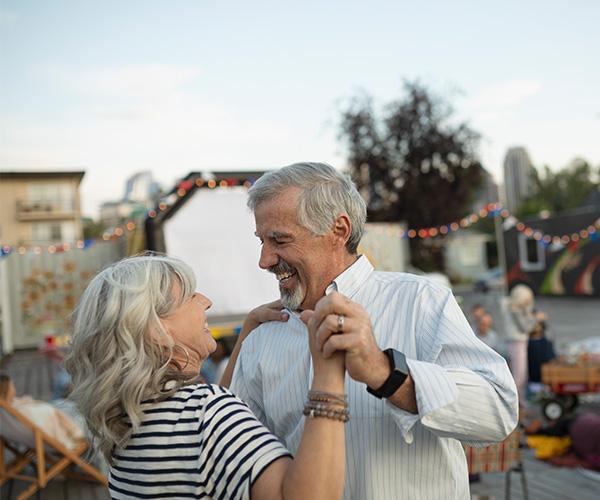 Two people holding each other while dancing outside.