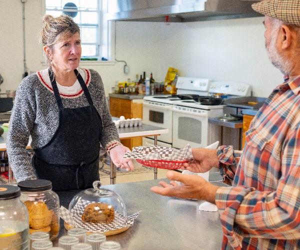 A baker interacting with a customer over the counter. 