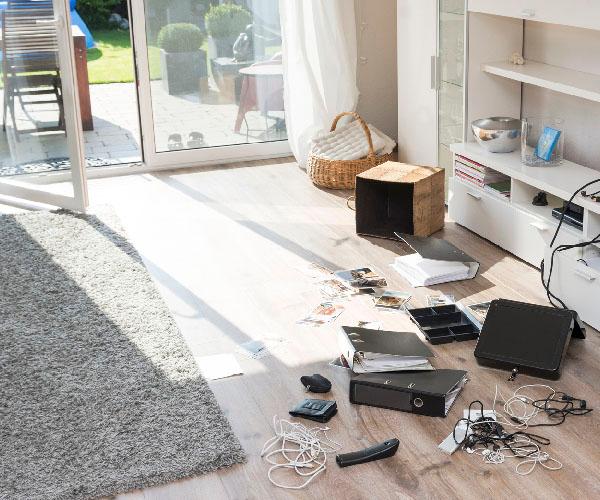 A living room that has cords and broken items on the floor with an open glass door.
