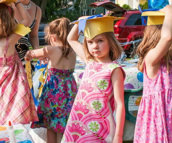 Four children with a hand on their graduation hat.