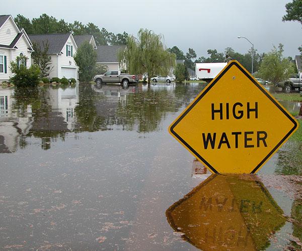 A flooded neighborhood with a yellow sign submerged in the water.