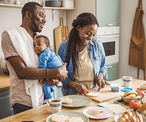 A family of three preparing sandwiches on the kitchen counter. 