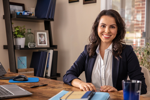 A person with medium brown hair sitting at a desk in an office.